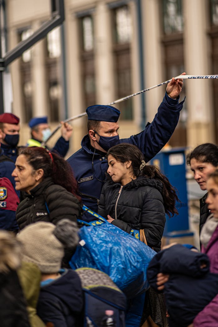 our-experience People passing through a security checkpoint at Budapest train station under supervision.