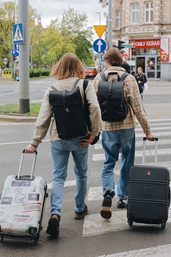 Two tourists crossing a street with suitcases in Poland. Urban travel scene.