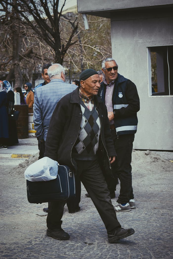 about-02 Elderly man carrying a bag, walking in an urban community setting during the day.